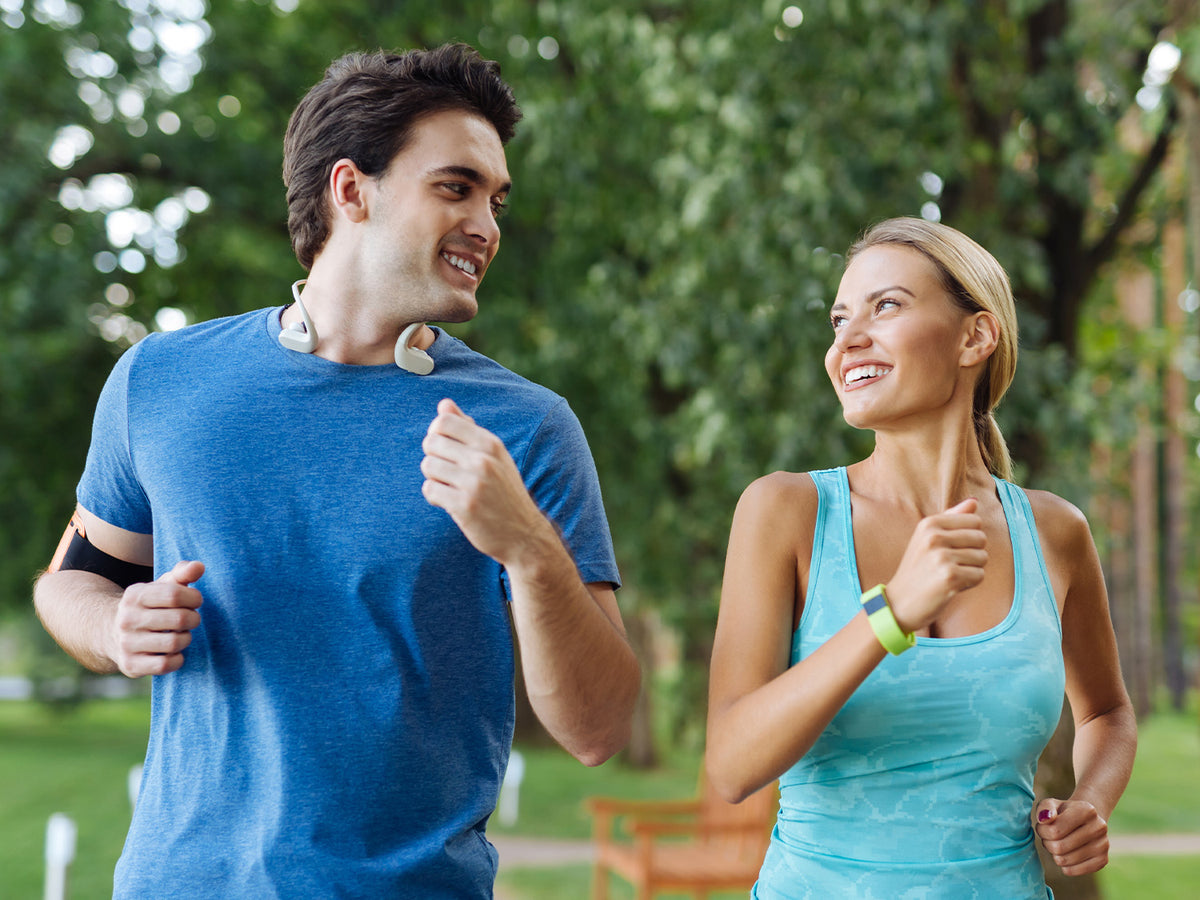 Smiling man and woman jogging outdoors together, highlighting active lifestyle and fitness supported by probiotics.