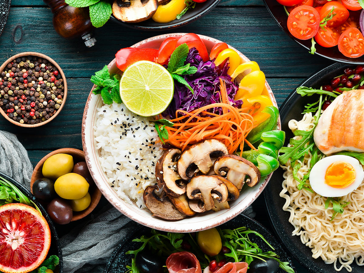 A vibrant selection of healthy foods including vegetables, mushrooms, rice, boiled egg, and grilled chicken, presented in bowls, emphasizing a balanced diet.